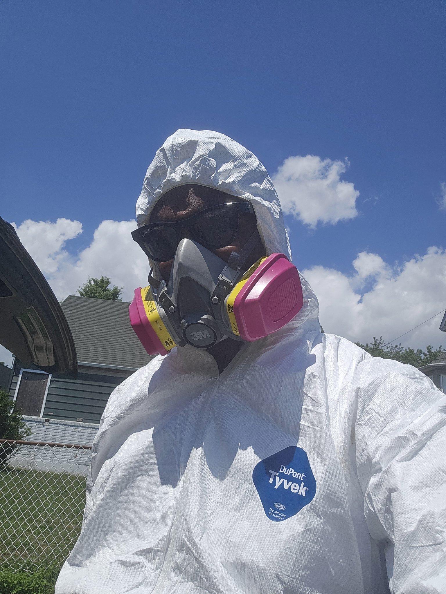 Chimeodo Uche wearing protective coveralls and a respirator during a field visit