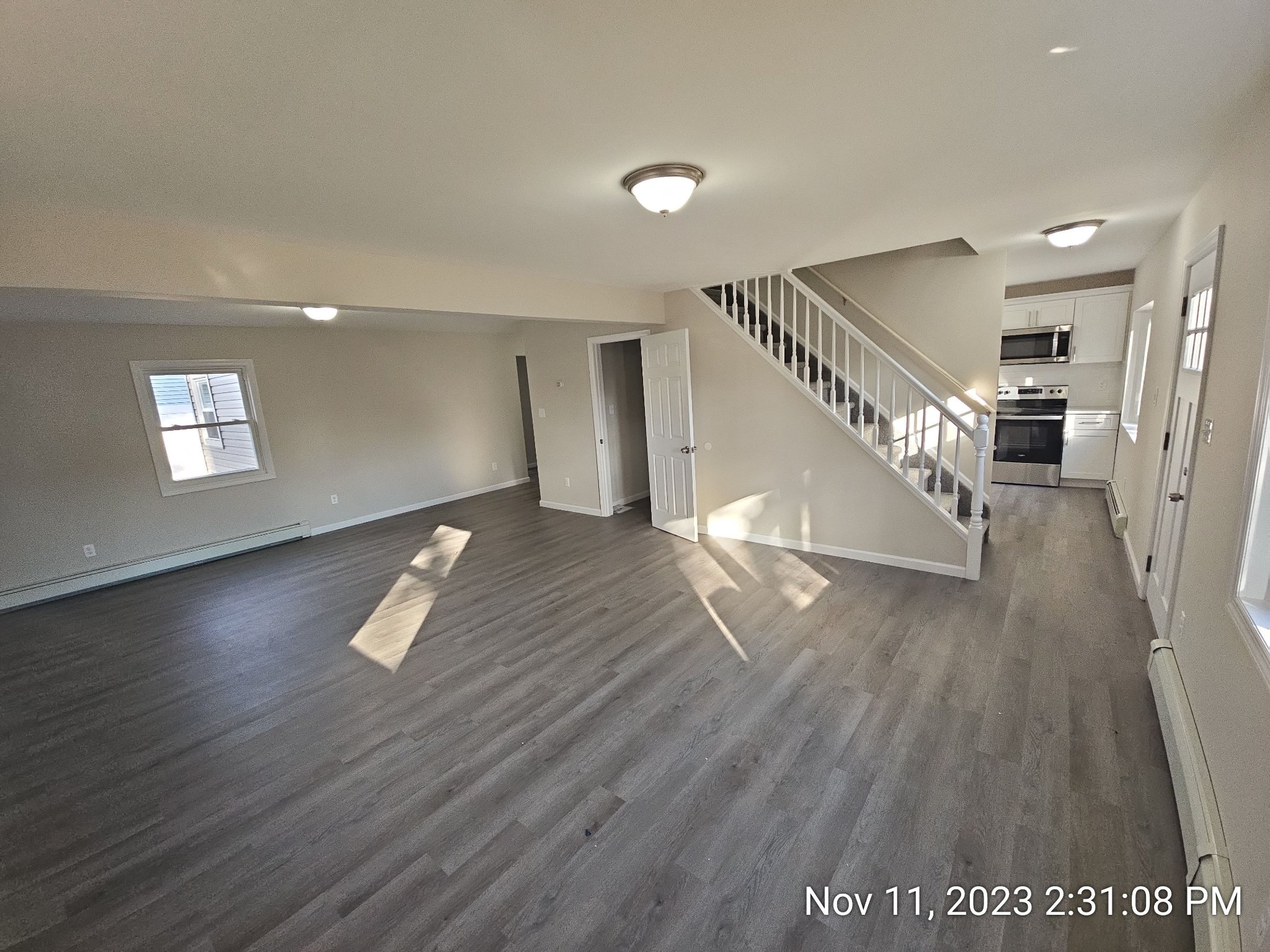 Renovated open living area with new flooring, paint, lighting, staircase, and kitchen