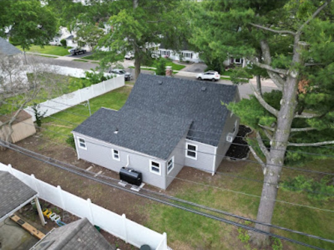 Aerial view of a renovated home with a completed asphalt-shingle roof
